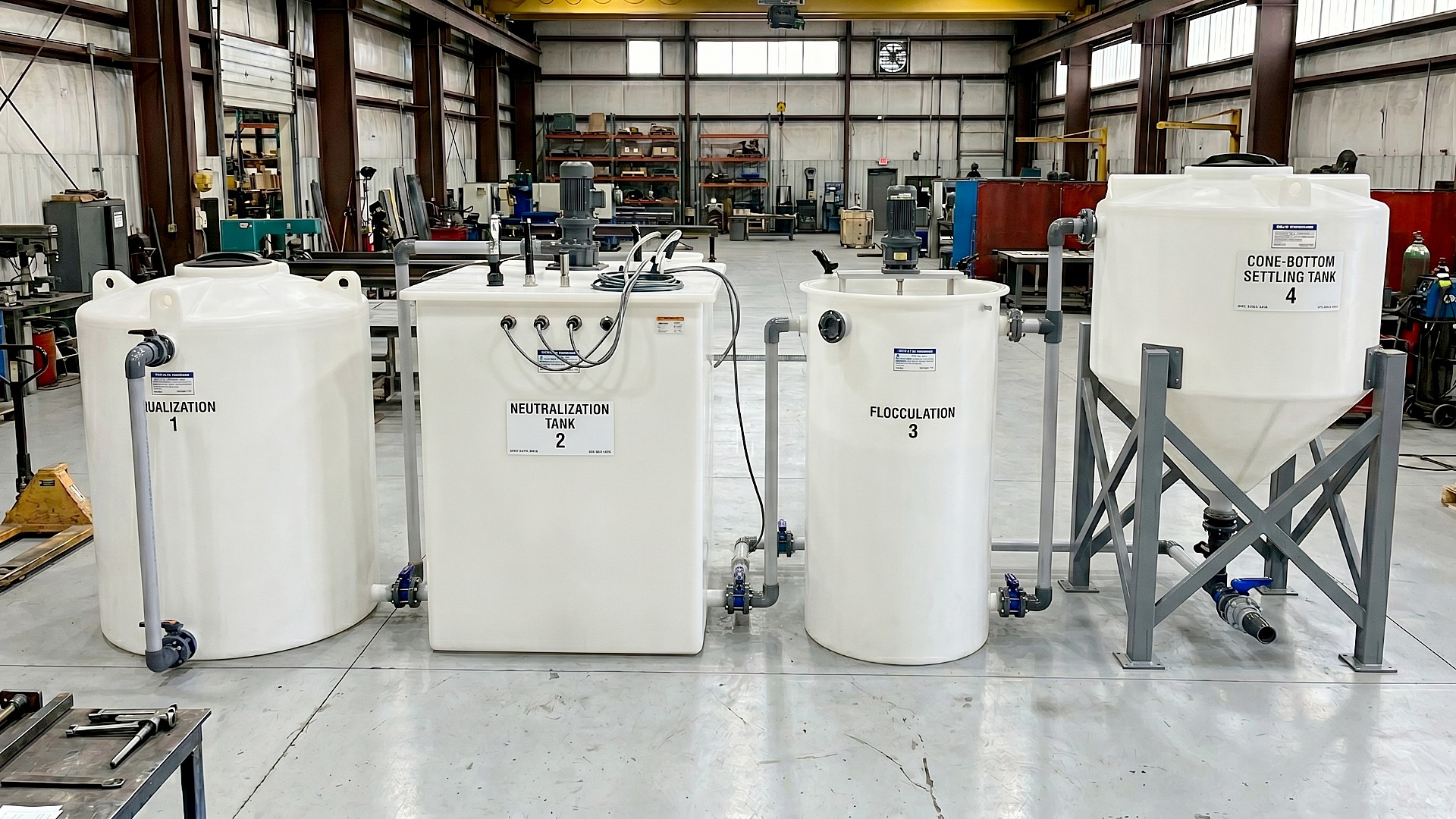 Custom fabricated industrial wastewater treatment train featuring tanks in sequence for neutralization and settling