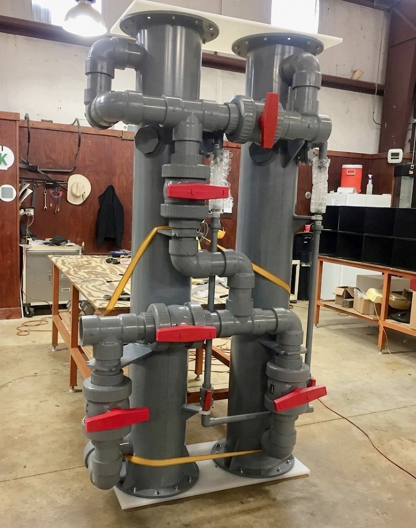 A row of three polyethylene storage tanks with blue flexible 