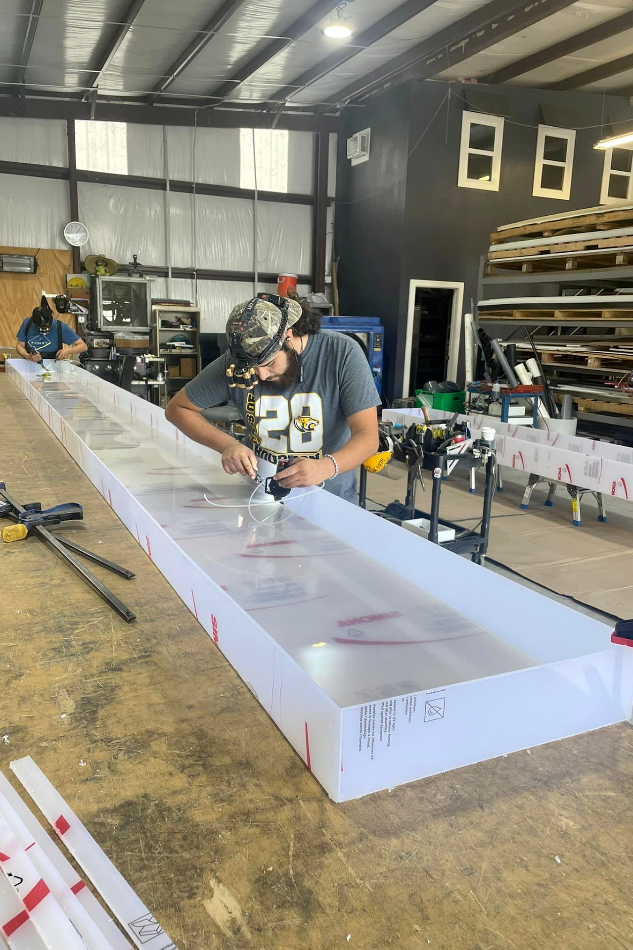 A technician performs plastic welding on a long, custom-fabricated polypropylene containment box