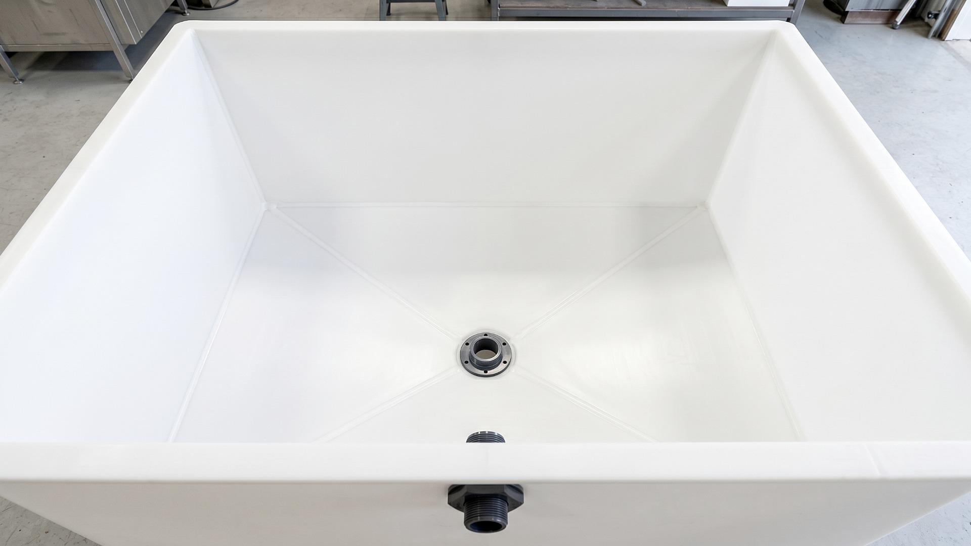 Overhead, looking down view of a custom, open top polypropylene tank with a sloped bottom and central drain fitting