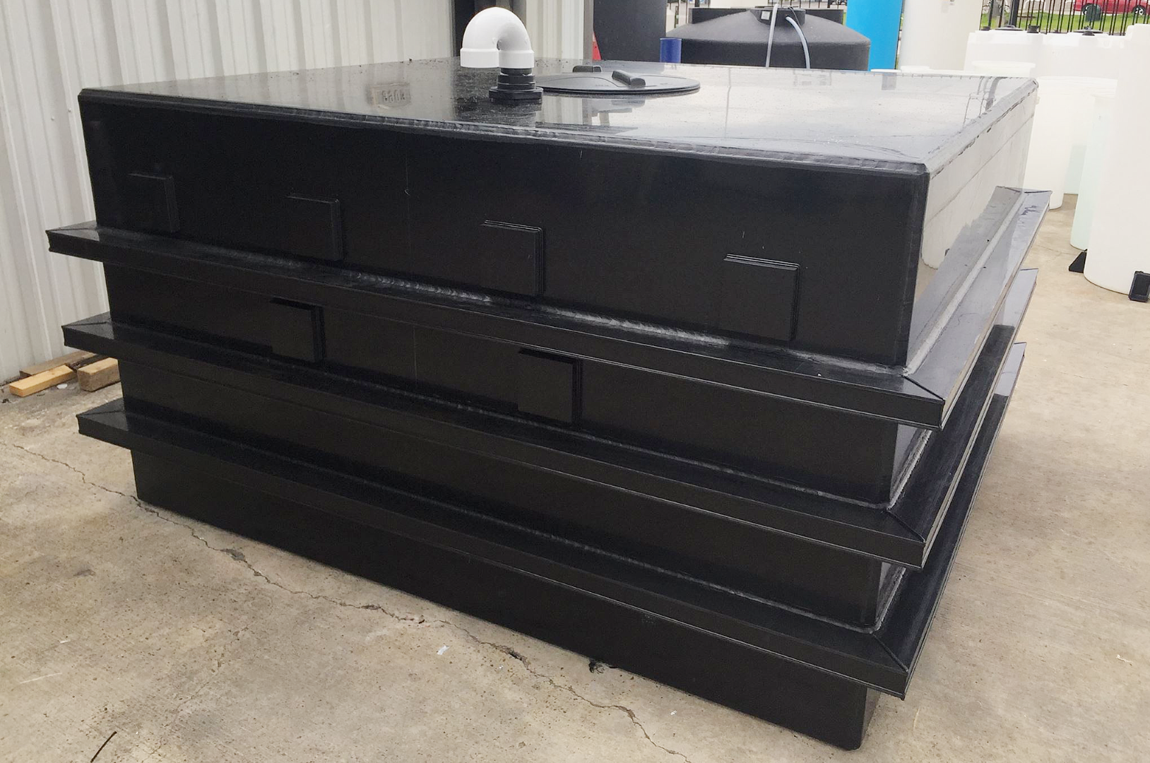 Large polypropylene box tank with external reinforcement ribs, a PVC u-vent, and manway lid