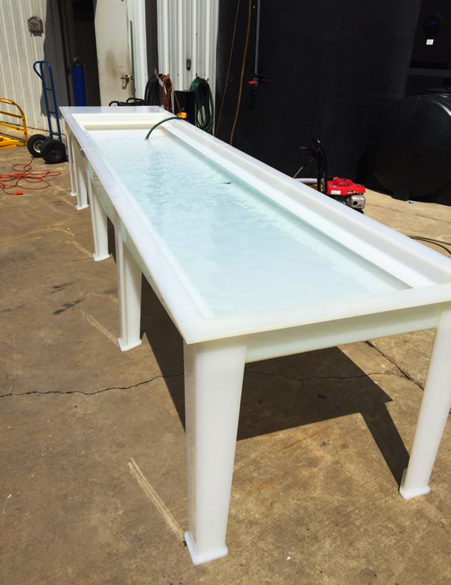 An elongated and elevated custom made polypropylene liquid dip table supported by four tapered heavy-duty plastic legs