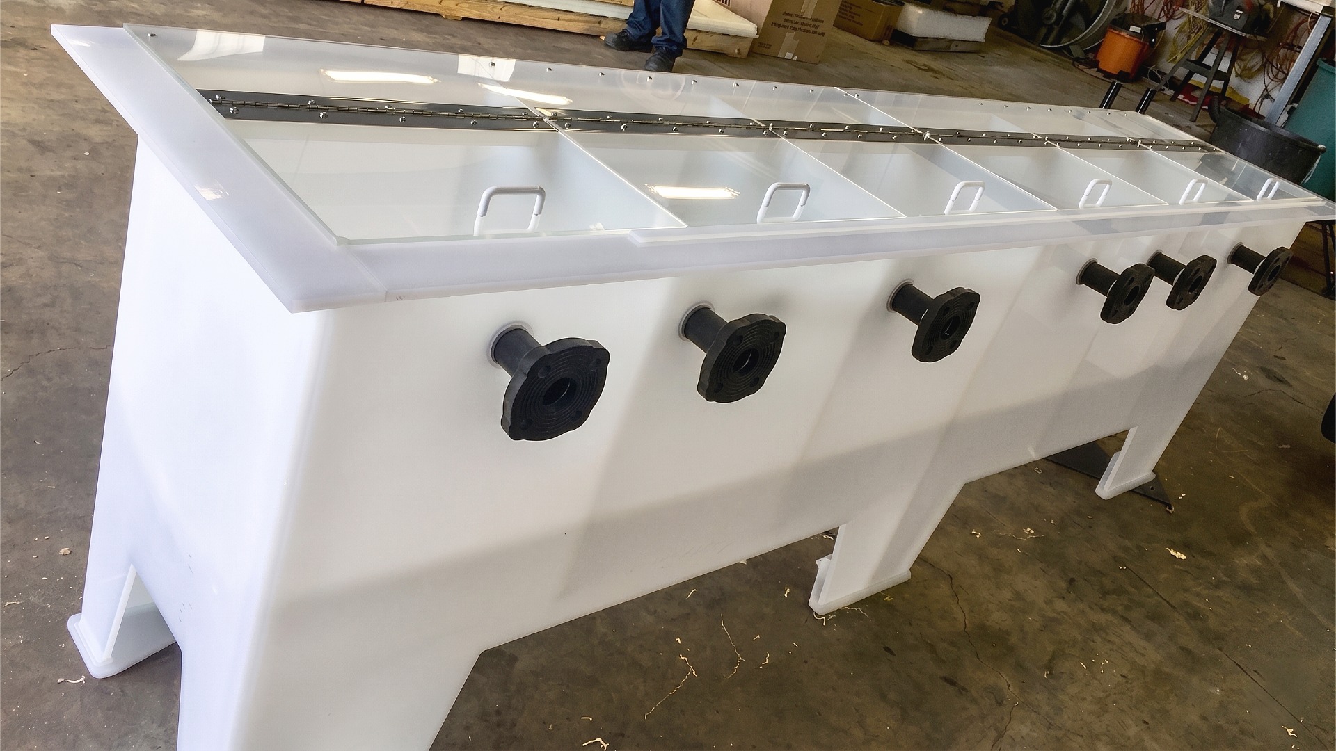 Image of a six basins-in-one tank, each with individual, hinged, clear lid and an attached black, flange inlet port
