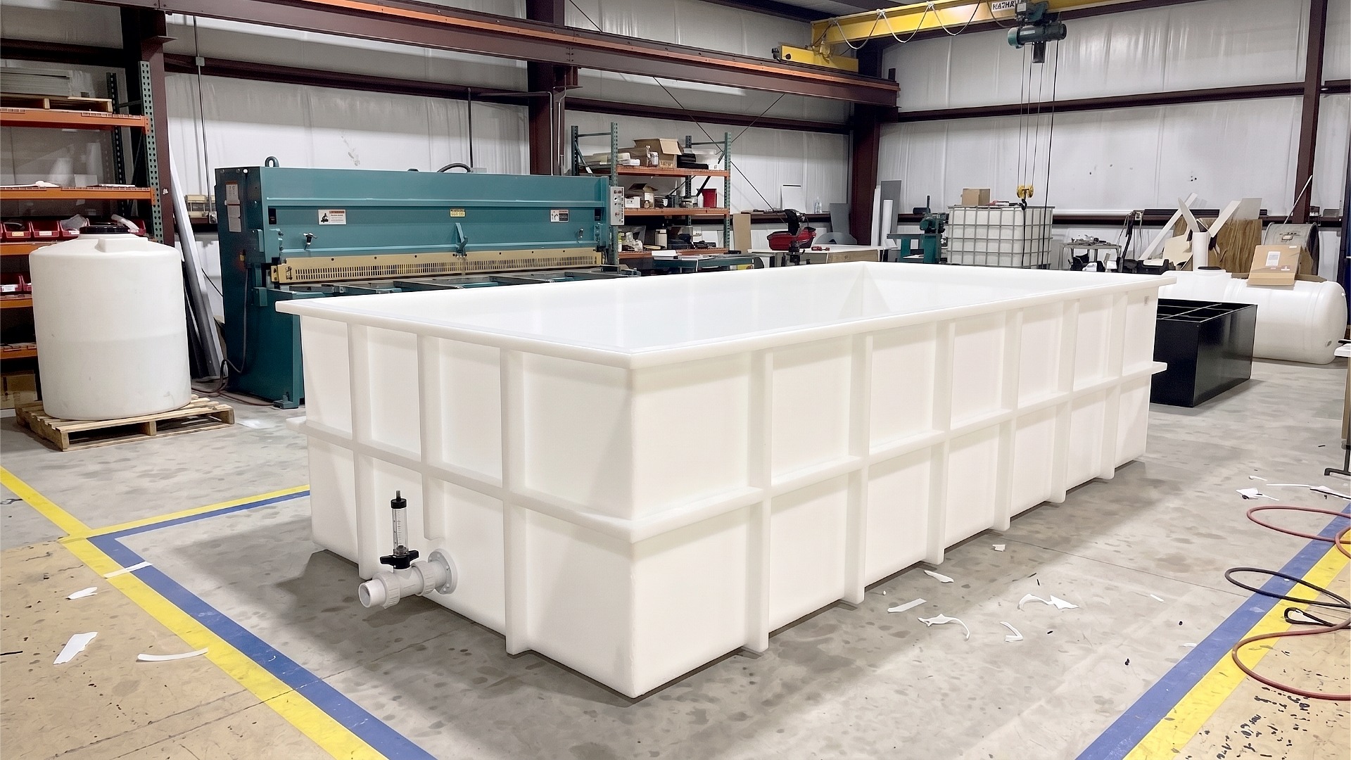 A long, rectangular, open top custom polypropylene chemical stripping tank with rib reinforcements and drain valve.