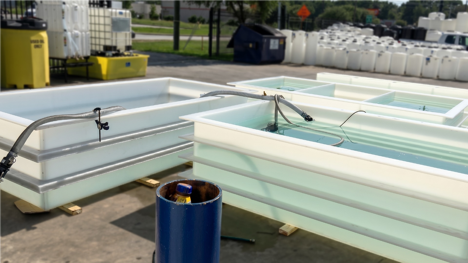 Three custom made polypropylene tanks filled with water for leakproofness testing in an outdoor staging area