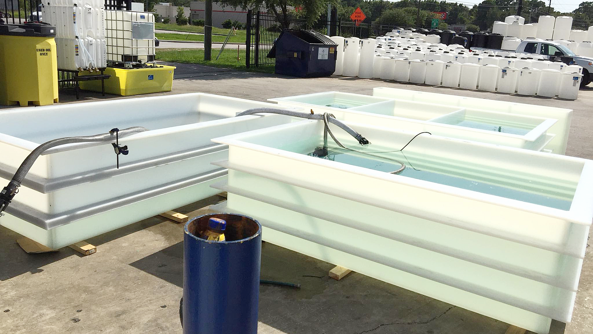 Three custom made polypropylene tanks filled with water for leakproofness testing in an outdoor staging area