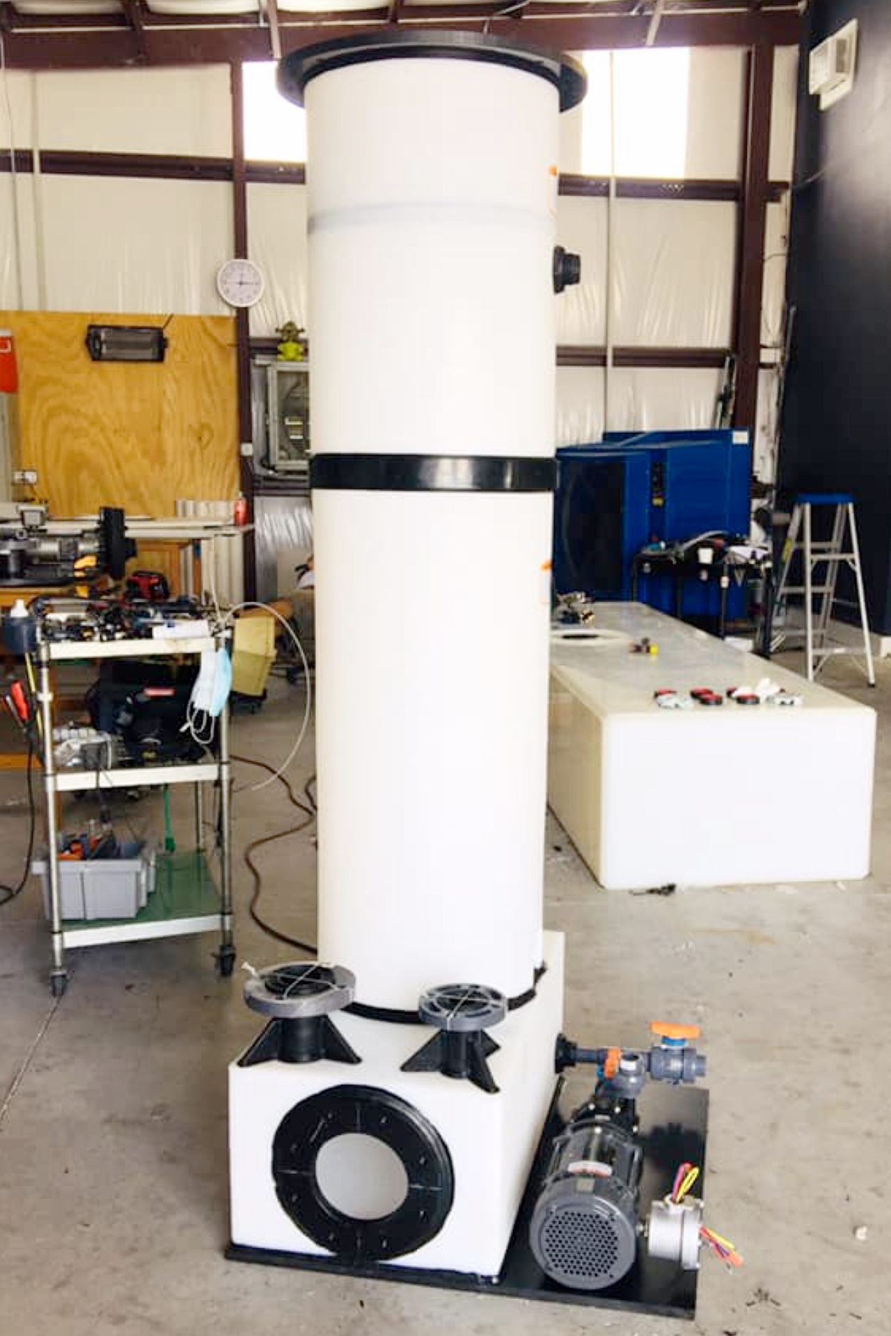 An industrial processing unit with a vertical tower, box base mount, integrated pump, and valve manifold