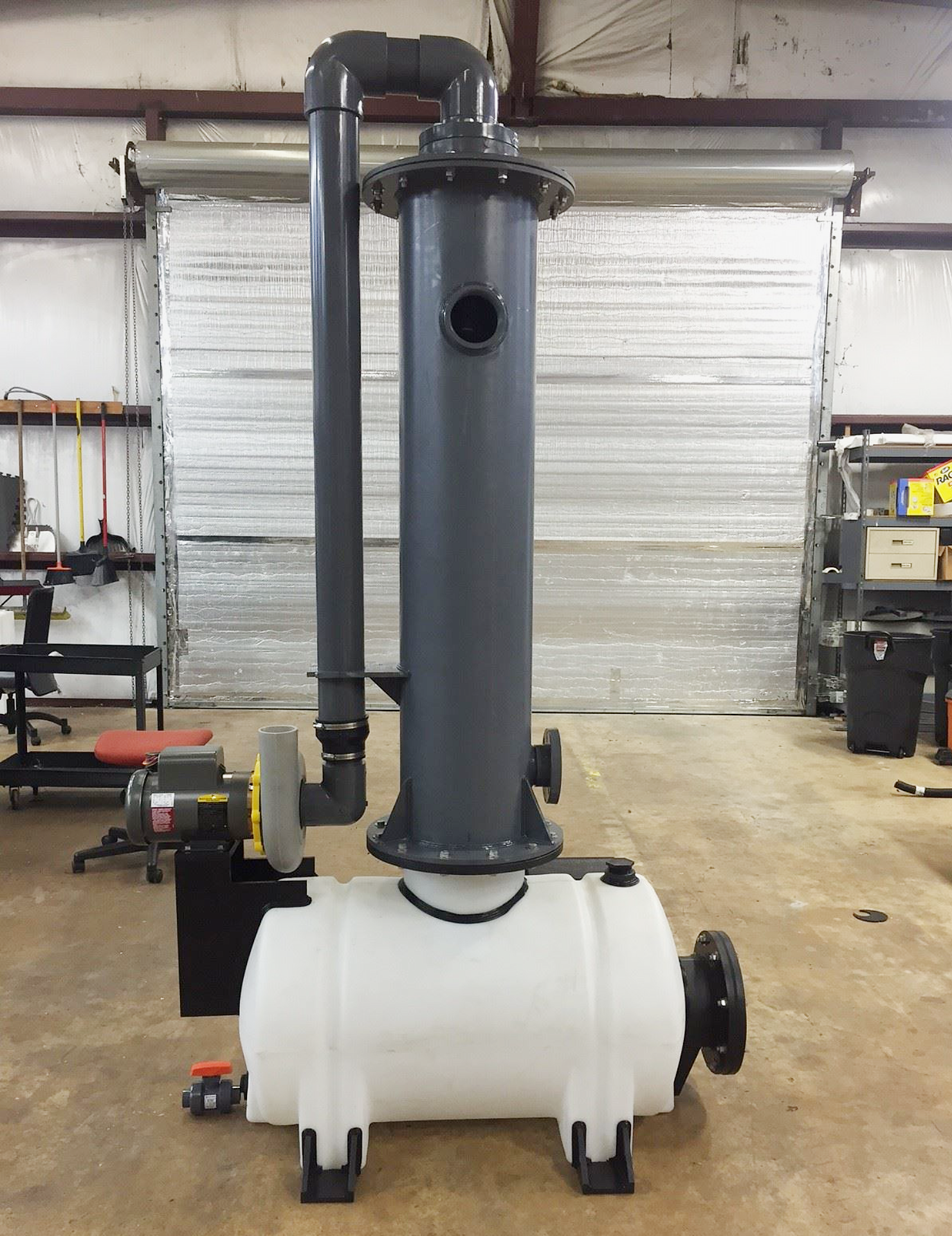 Side profile of an industrial processing unit featuring a leg tank, a tall vertical fume handling tower, and piping