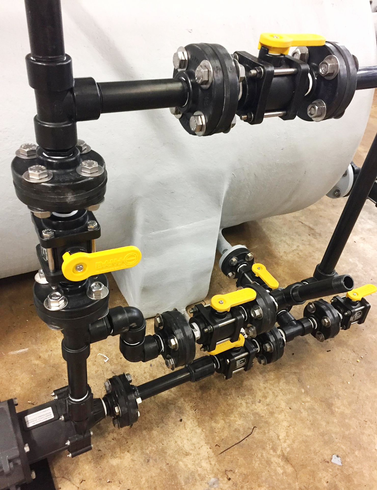 A complex industrial manifold system made from PVC pipes with multiple ball valves mounted to a custom tank