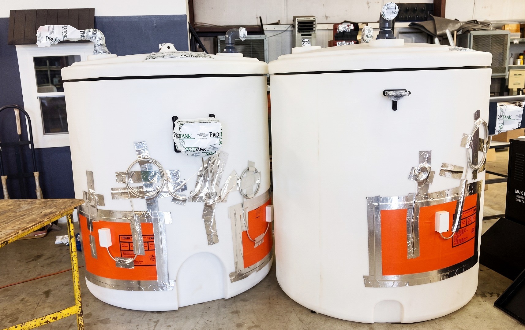 Two cylindrical tanks in a workshop fitted with heat trace pads and reflective insulation tape