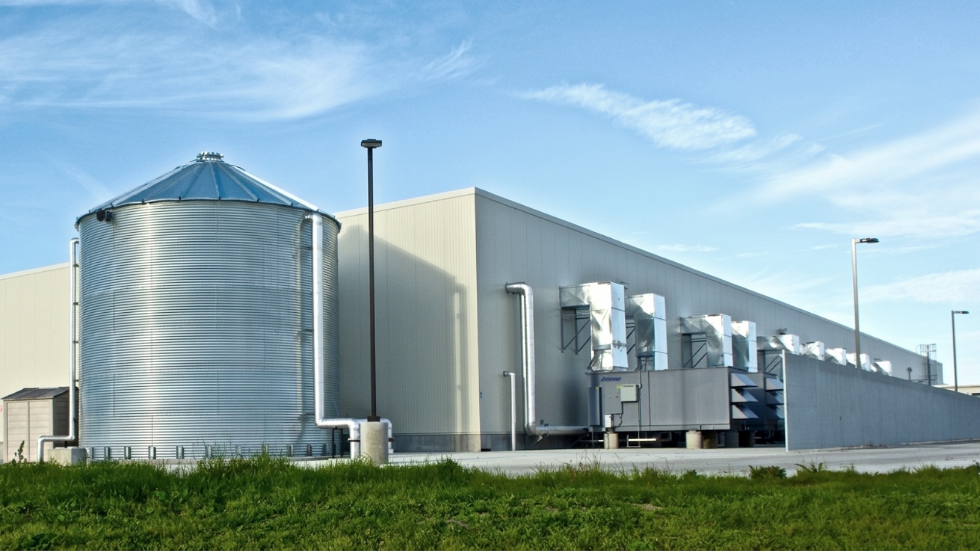 An image showing a tall galvanized steel water tank installed next to an enterprise scale data center where the tank is taller than the building