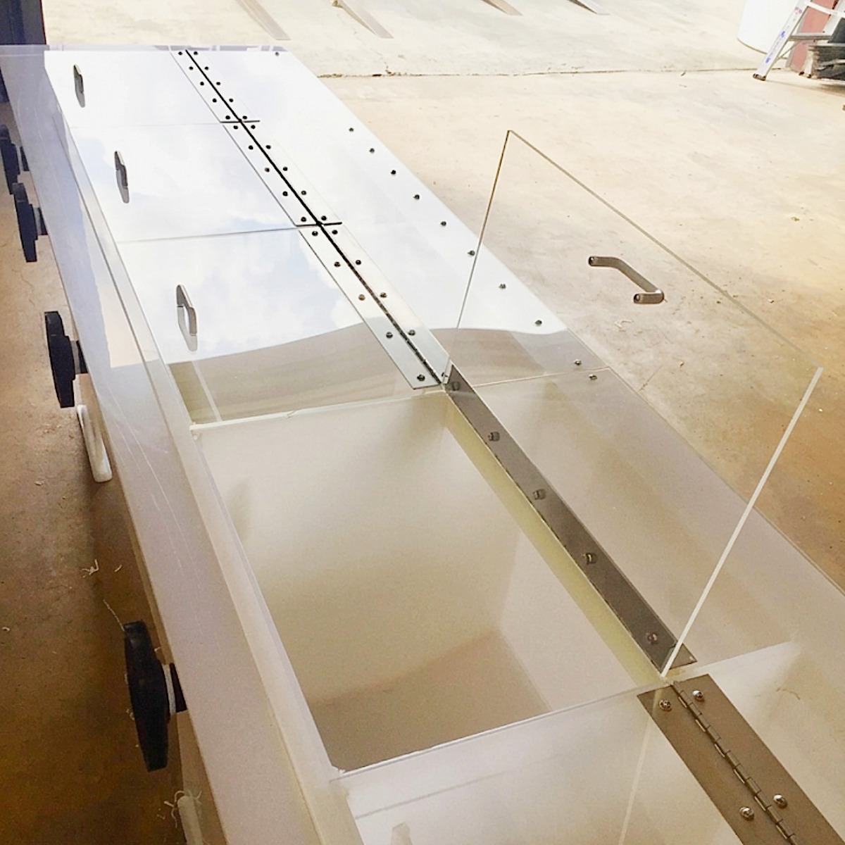 Long white storage tank with multiple compartments, clear acrylic hinged lids with stainless steel hardware and handles