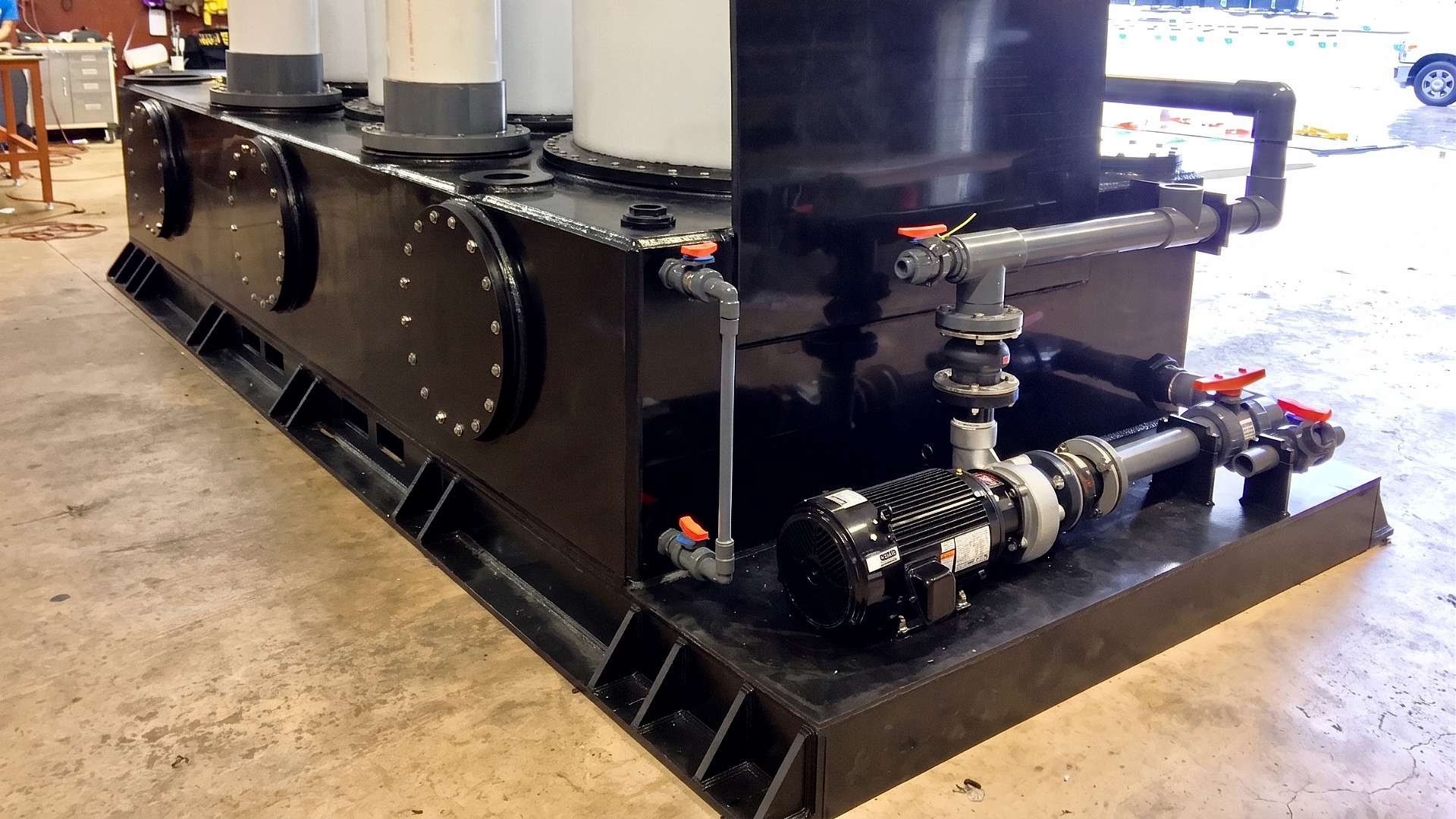 A close up of a chemical liquid and vapor handling tank system with pump, piping, valves, and columns