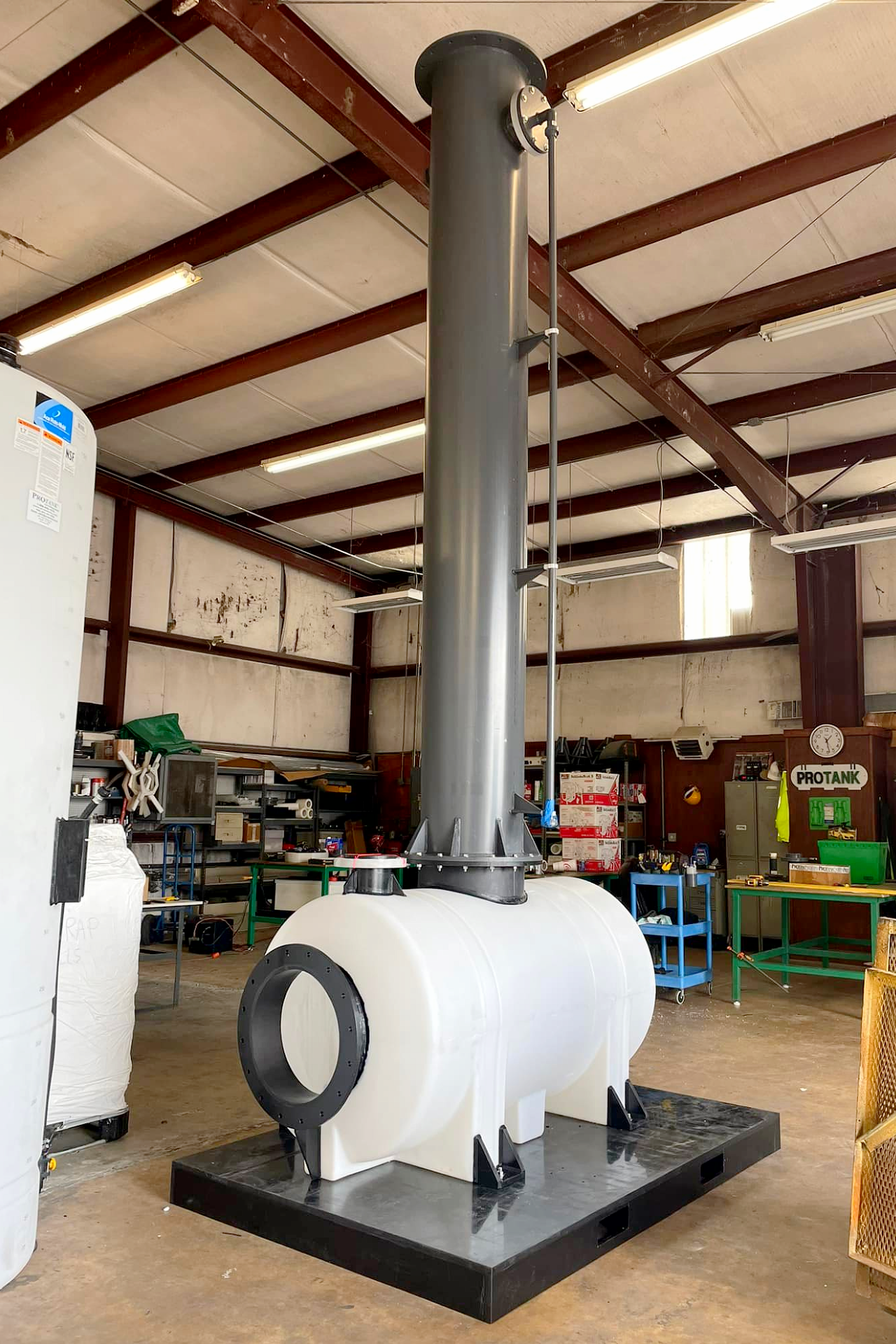 A custom leg tank system on a structural base with a tall vertical fume scrubber stack for chemical exhaust