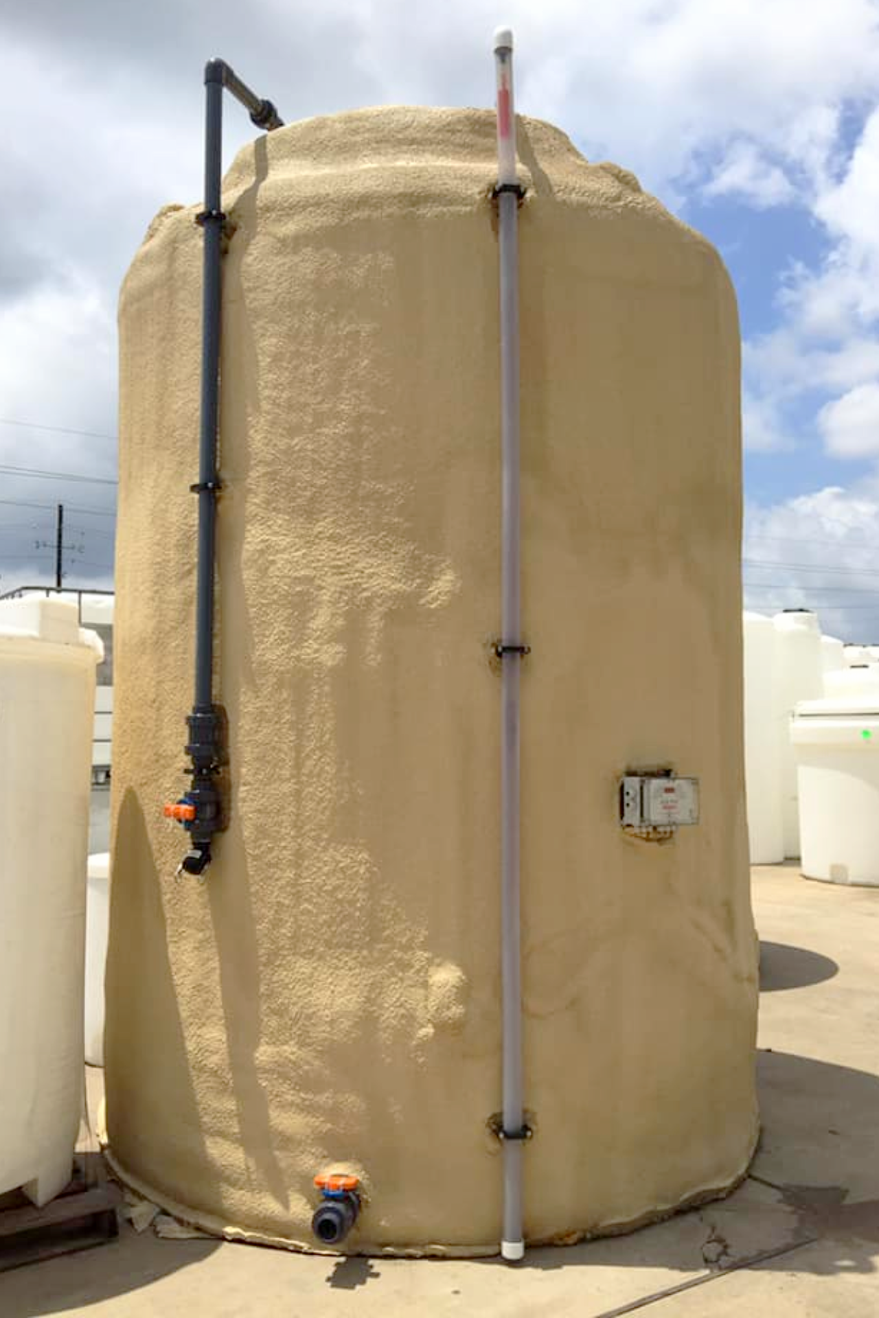 A large vertical storage tank with polyurethane foam insulation, external black fill line, and dip tube gauge