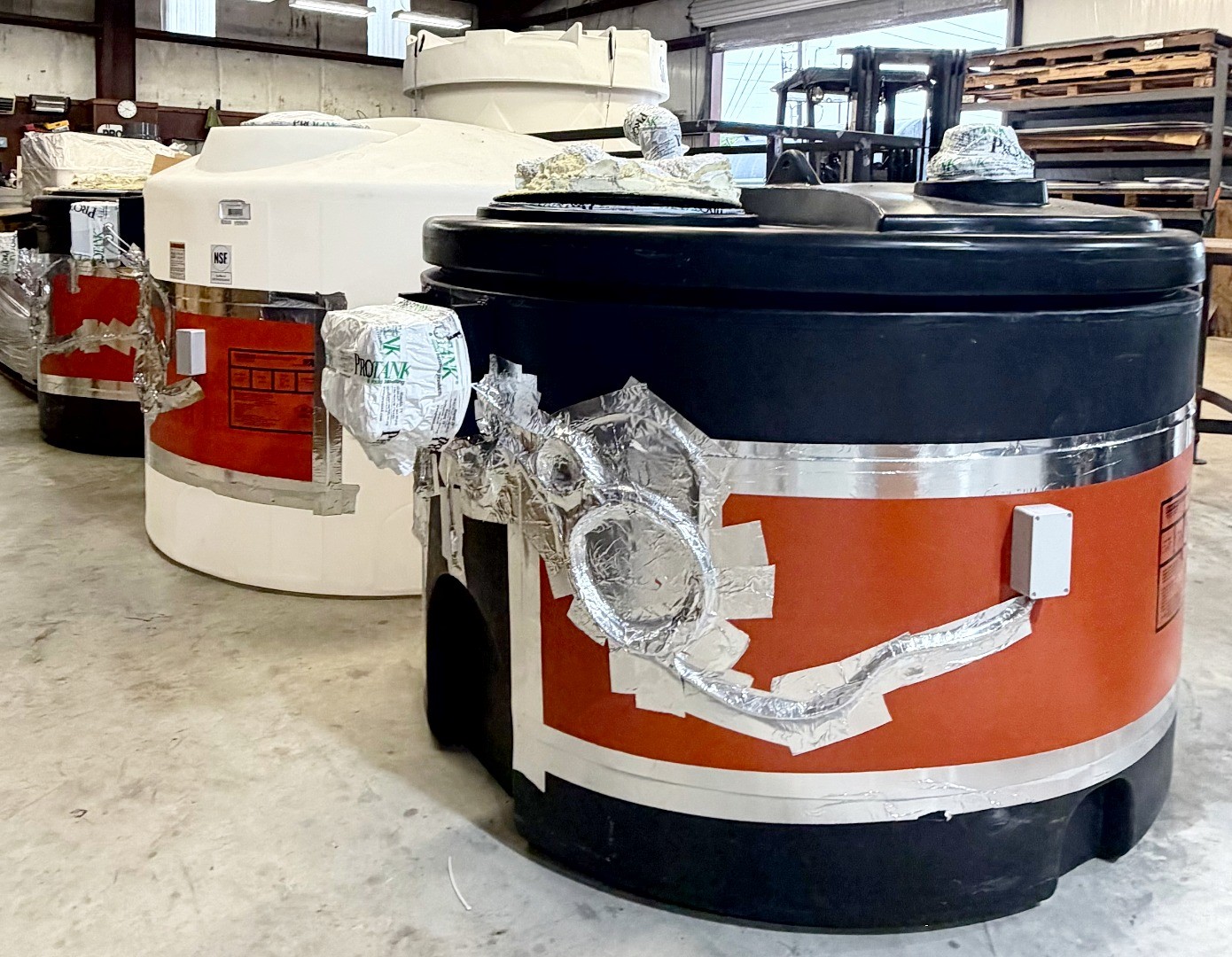 Image showing inside fabrication facility where three polyethylene tanks have been customized with fittings and electrical heat tracing