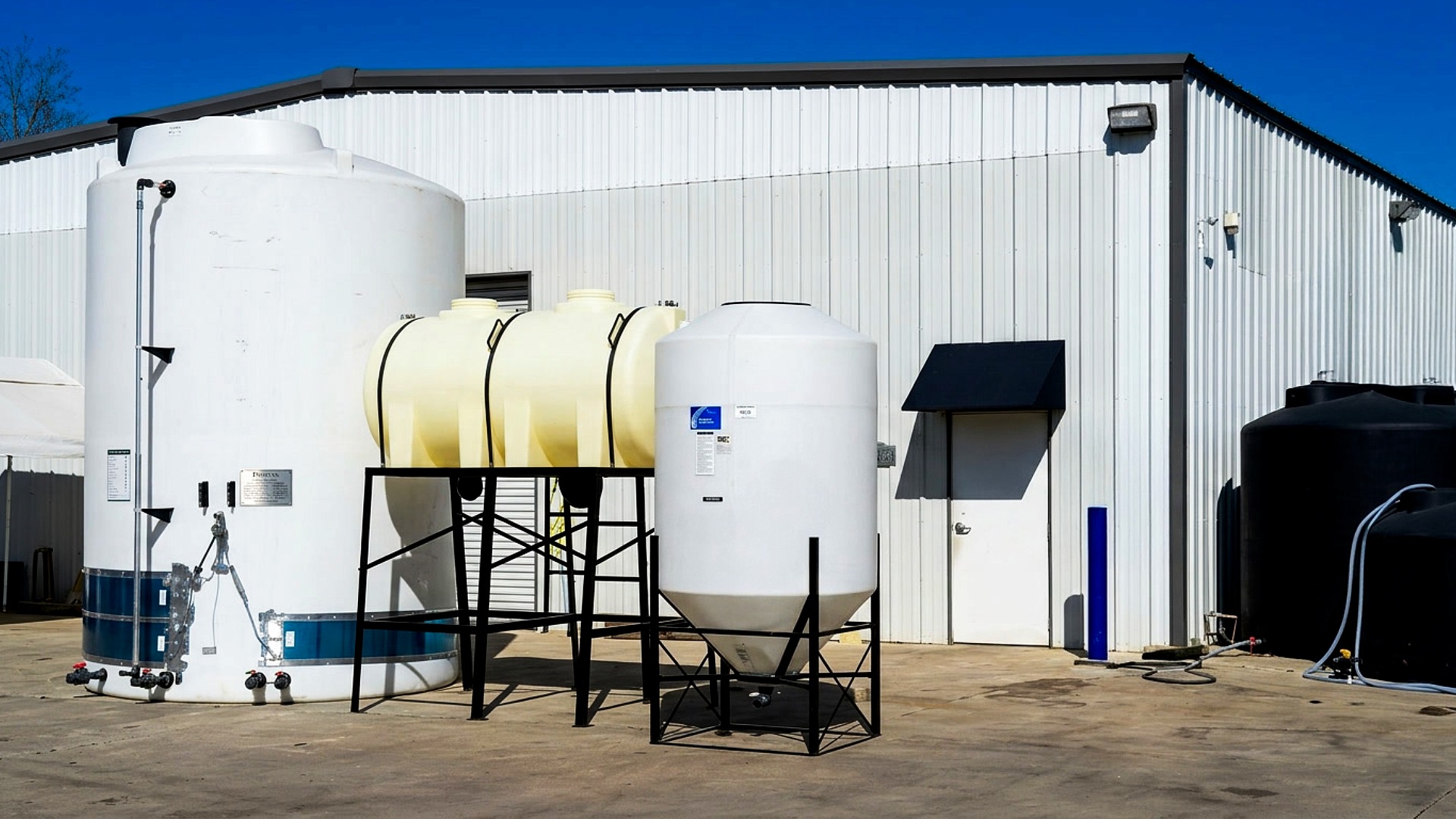 Protank facility with large bulk poly tank with heat tracing and add-ons, custom modified horizontal leg tank on stand, and outfitted cone bottom tank