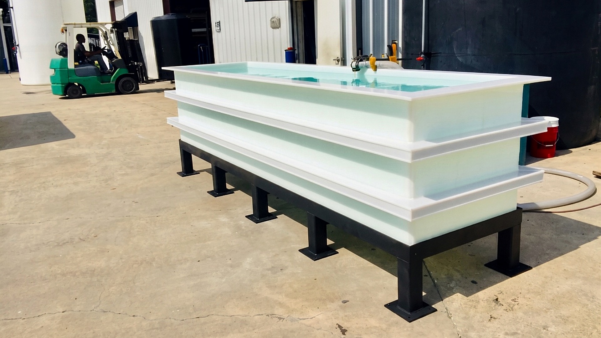 Long custom polypropylene anodizing tank with integral structural flanges and secondary containment base tray, water-tested